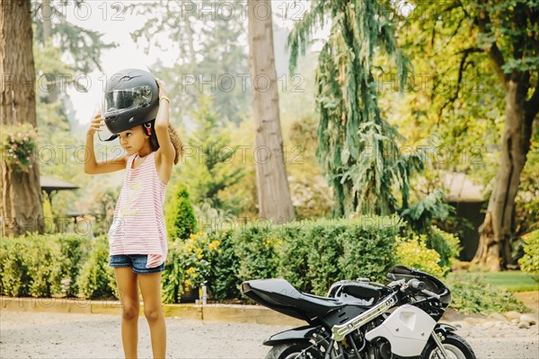 Mixed race girl putting on helmet