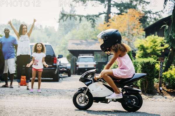 Girl riding miniature motorcycle on street