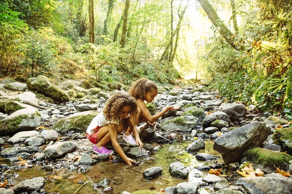 Mixed race sisters exploring stream