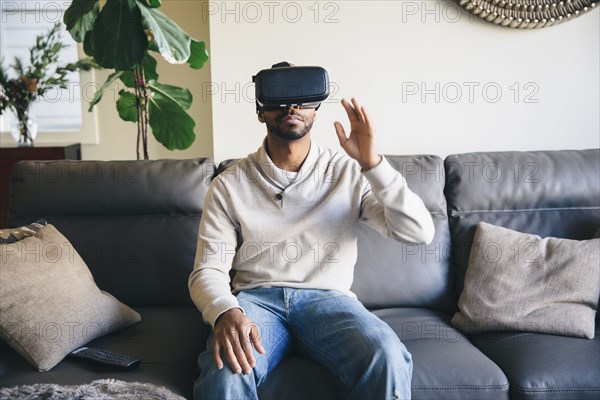 Mixed race man using virtual reality goggles