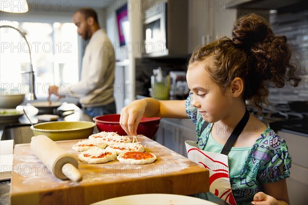 Mixed race girl cooking in kitchen