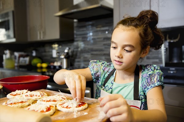 Mixed race girl cooking in kitchen