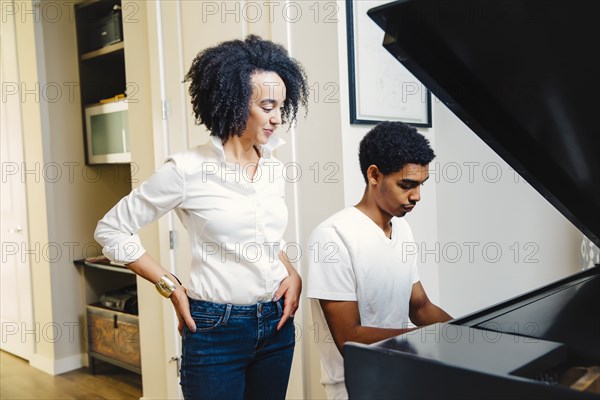 Mother watching son play piano