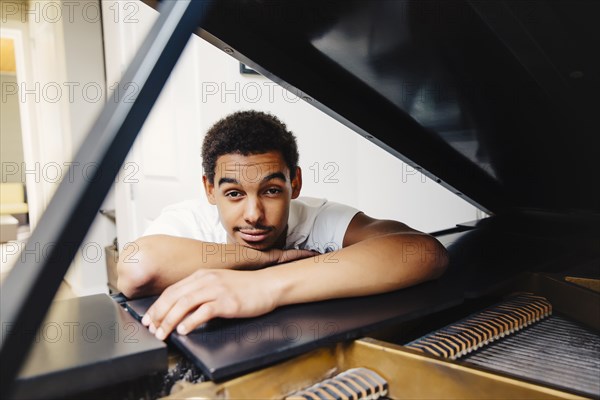 Mixed race man leaning on piano