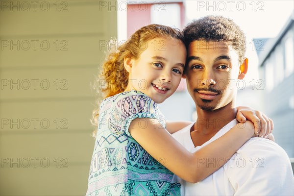 Mixed race brother holding sister outdoors