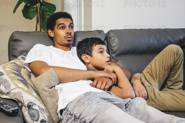 Mixed race brothers watching television on sofa