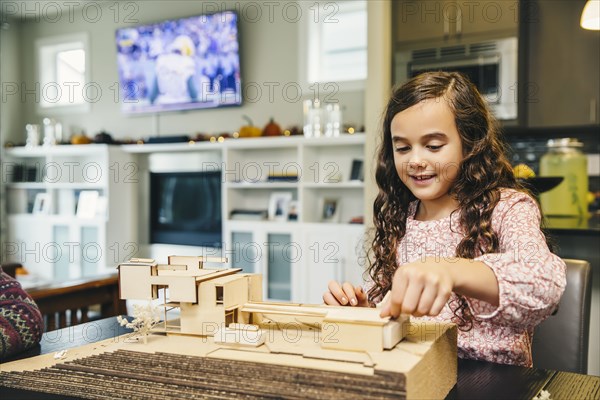Mixed race girl building model house