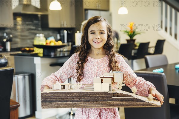 Mixed race girl holding model house