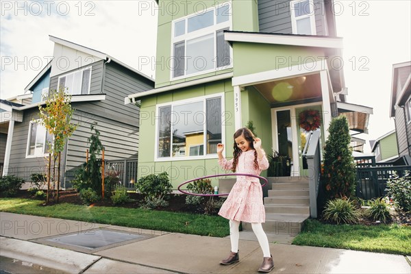 Mixed race girl twirling hoop on sidewalk