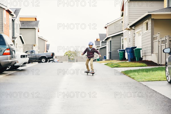Mixed race boy riding skateboard on street