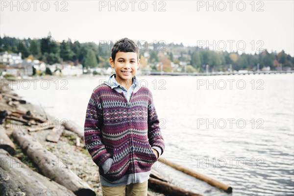 Mixed race boy walking on logs at lake