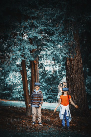 Mixed race children using virtual reality goggles outdoors