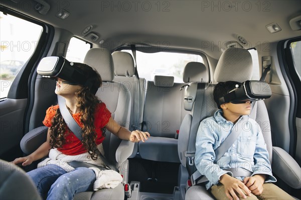 Mixed race children using virtual reality goggles in car