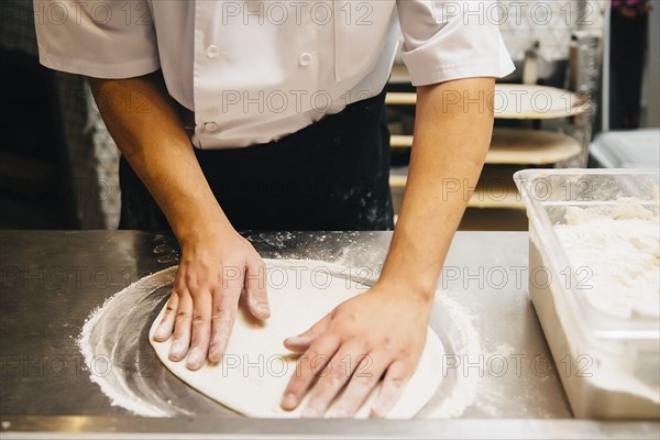 Chef shaping pizza dough in restaurant kitchen