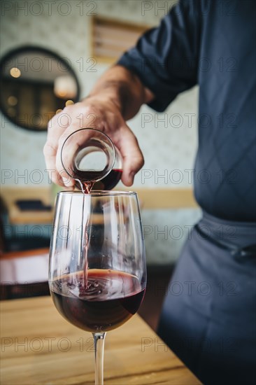 Caucasian waiter pouring wine in cafe