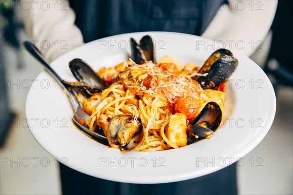 Mixed race waitress holding plate of seafood and pasta