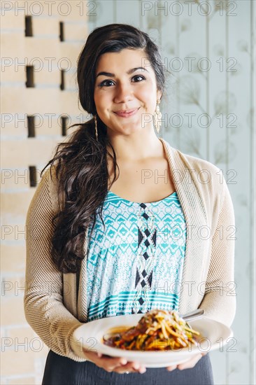 Mixed race waitress holding plate of pasta