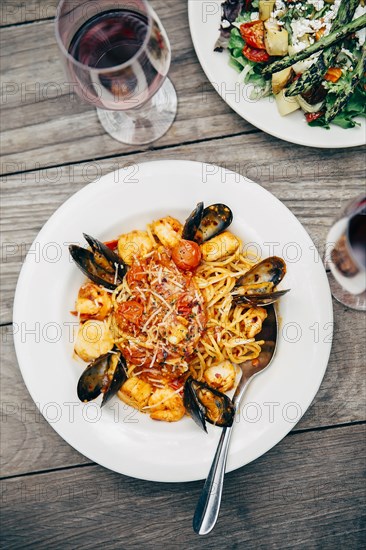 Plates of salad and pasta with wine glasses