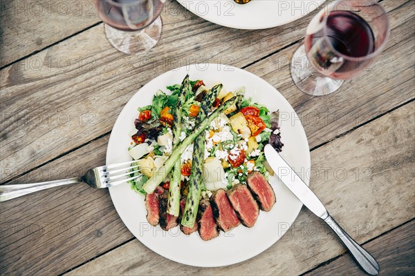 Plate of salad and meat with wine glasses