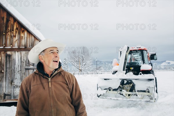 Caucasian farmer and tractor in snowy field