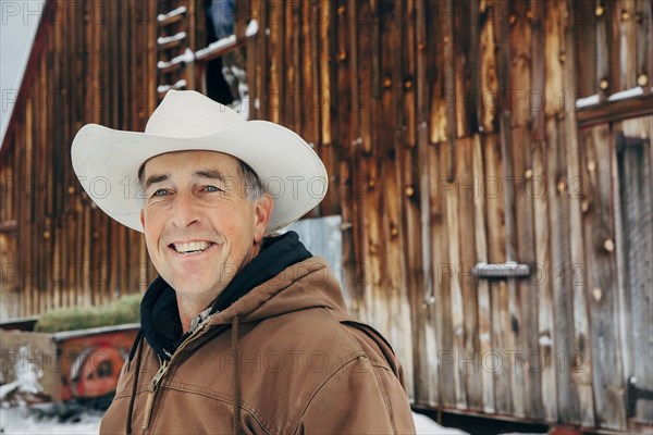 Caucasian farmer smiling near snowy barn