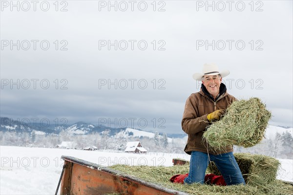 Caucasian farmer hauling hay in snowy field