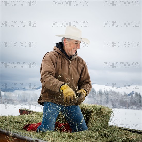 Caucasian farmer kneeling in hay