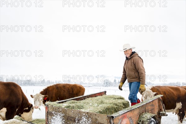 Caucasian farmer hauling hay in snowy field