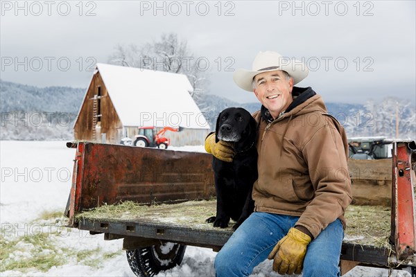 Caucasian farmer hugging dog in snowy truck