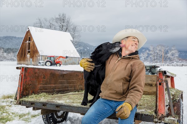 Dog licking face of Caucasian farmer in snowy truck