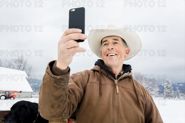 Caucasian farmer using cell phone in snowy field