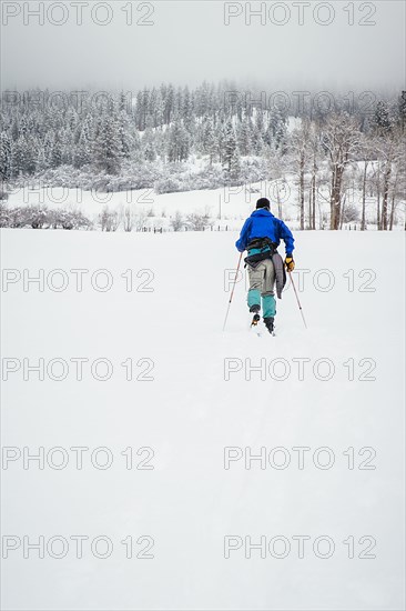 Caucasian woman cross-country skiing in snowy field