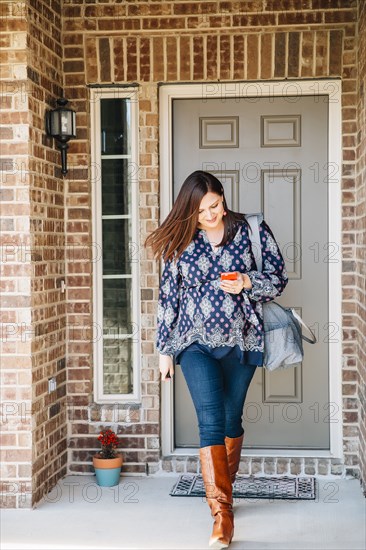 Hispanic woman walking on front stoop