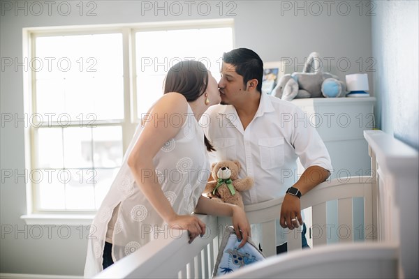 Hispanic couple kissing in nursery