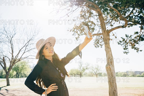 Chinese woman taking selfie in field