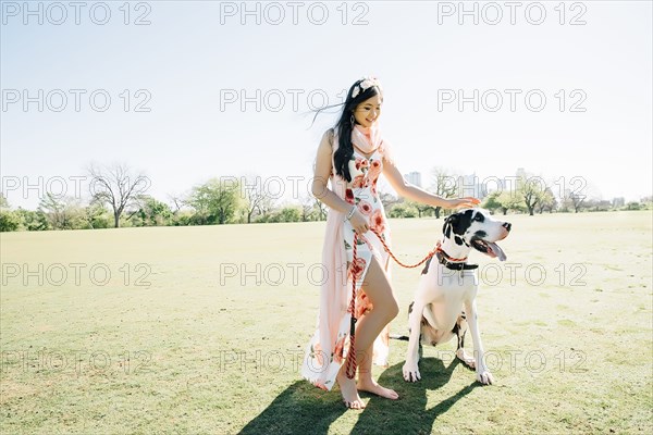 Chinese woman walking dog in field