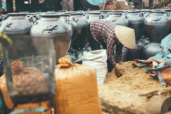 Vendor lifting grain into pots in market