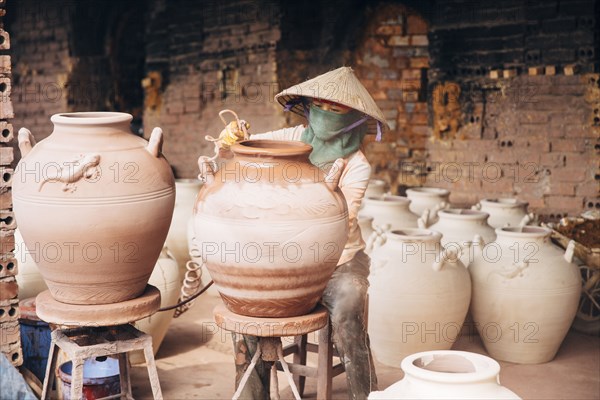 Artist painting pots in factory
