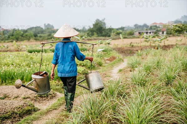 Farmer carrying water in rural crop field