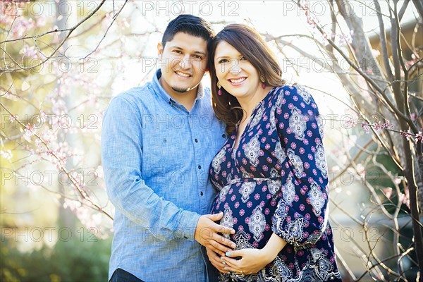 Pregnant Hispanic couple smiling outdoors