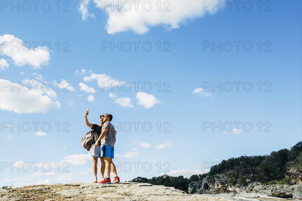 Caucasian friends taking selfie on hilltop