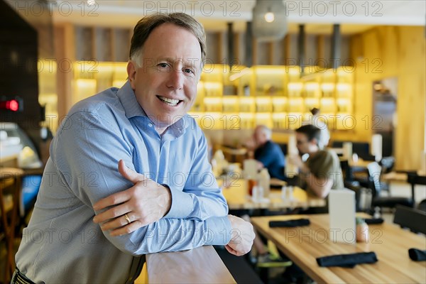 Smiling Caucasian man leaning on banister at restaurant