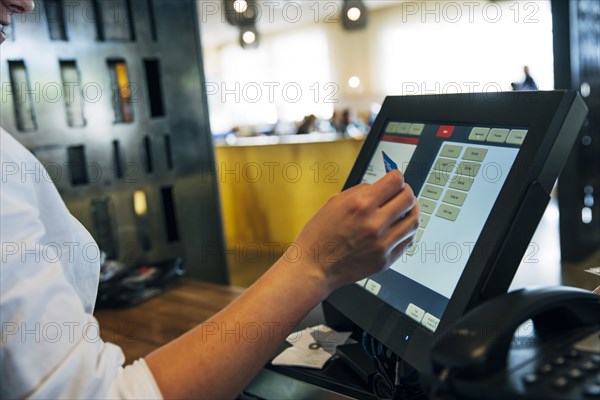 Caucasian cashier using touch screen to process credit card payment