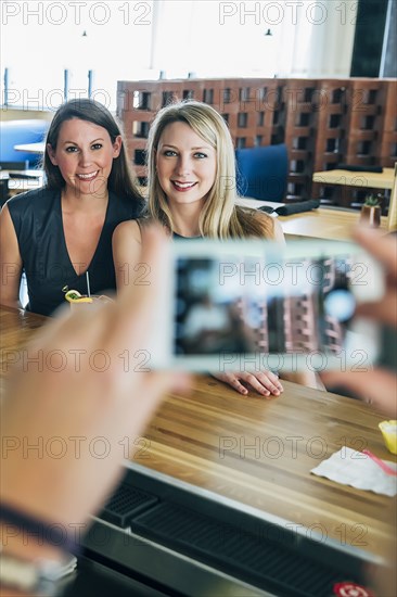 Caucasian bartender taking cell phone photograph of customers