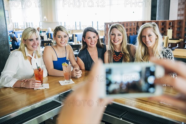 Caucasian bartender taking cell phone photograph of customers