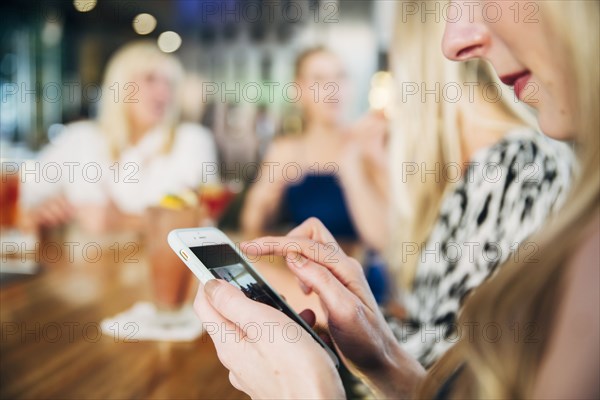 Caucasian woman using cell phone at bar