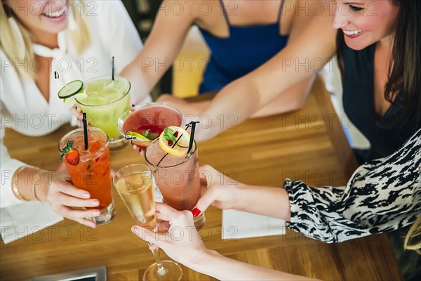 Caucasian women toasting at bar with cocktails