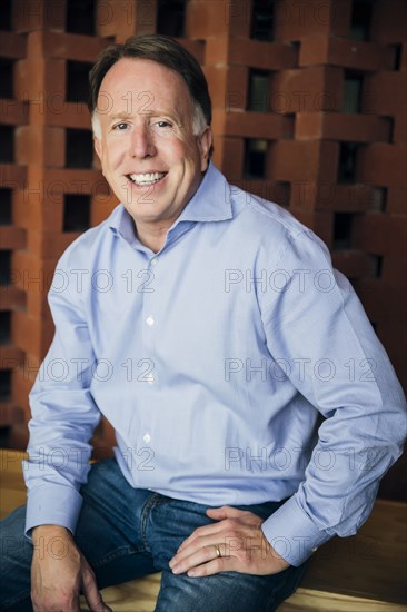 Smiling Caucasian man wearing jeans sitting