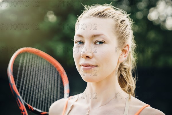 Smiling Caucasian woman holding tennis racket
