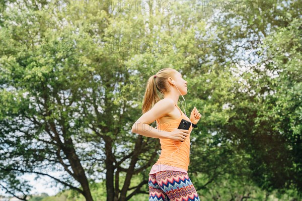 Caucasian woman listening to earbuds while running